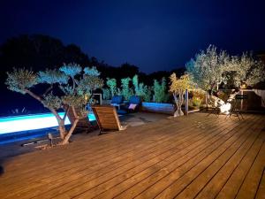 een houten terras met stoelen en bomen in de nacht bij Villa Parenthèse in Saint Alban Auriolles