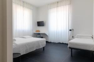 two beds in a room with white curtains at AMARENA B&B Porto Recanati in Porto Recanati