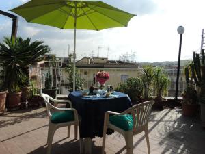 una mesa y sillas con una sombrilla verde en el patio en Sinfonia di Napoli, en Nápoles