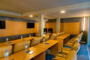 Legend Boutique Hotel في كيغالي: قاعة اجتماعات مع طاولات وكراسي خشبية
