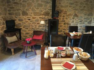 a dining room with tables and chairs and a stone wall at Le Clos Pen Kear in Plouarzel