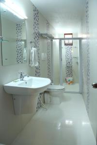 a white bathroom with a sink and a toilet at Chiramel Residency in Cochin