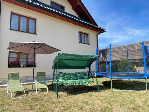 a yard with two chairs and an umbrella and a trampoline at Chalupa pod Tatrami in Liptovská Teplička