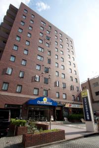 a large brick building with a blue canopy in front of it at Smile Hotel Sugamo in Tokyo