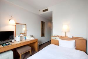 a hotel room with a bed and a desk with a mirror at Smile Hotel Sugamo in Tokyo +58 photos