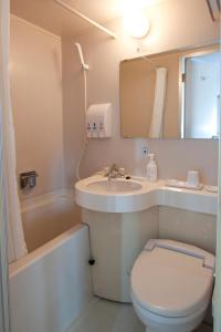 a bathroom with a sink and a toilet and a tub at Smile Hotel Sugamo in Tokyo