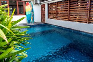 a swimming pool with a surfboard next to a house at House of Michella - Modern, Quiet & Central in Sanur