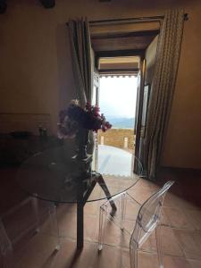 a glass table and chairs with a vase of flowers on it at Castello di Rocca Cilento in Rocca Cilento