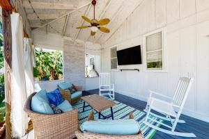 - une terrasse couverte avec une table, des chaises et une télévision dans l'établissement Kissing Palms, à Panama City Beach