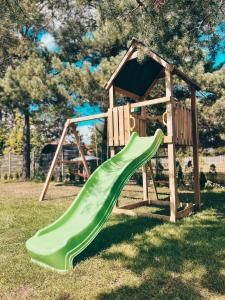 a green slide in front of a wooden playground at Projekt Warchały in Warchały