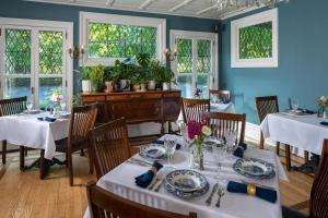 een eetkamer met witte tafels, stoelen en ramen bij Landmark Inn in Cooperstown
