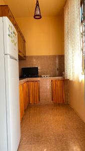 ゴニオにあるHoliday Home in Gonioのキッチン(白い冷蔵庫、オレンジ色のカーテン付)