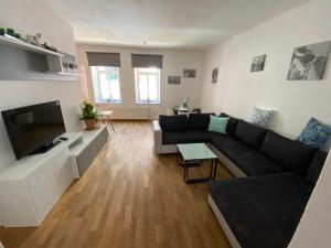 sala de estar con sofá negro y TV de pantalla plana en Apartsee Zell am See, en Zell am See