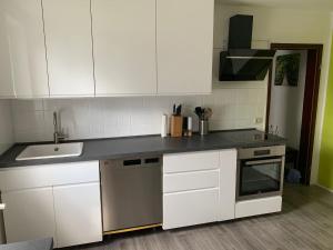 a kitchen with white cabinets and a sink at Ferienwohnung an der Oker in Altenau
