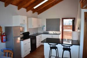 a kitchen with white cabinets and a black counter top at PA Sands Beach House Kowie River 9 Sleeper Pool in Port Alfred