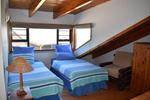 2 Betten in einem Zimmer mit einem Stuhl und einem Fenster in der Unterkunft PA Sands Beach House Kowie River 9 Sleeper Pool in Port Alfred
