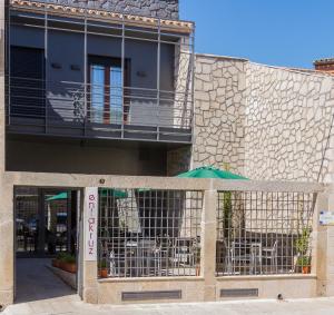 a building with a gate with tables and chairs at Enlakruz in Lagartera