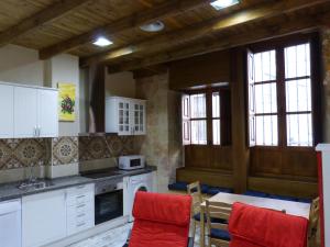 a kitchen with white cabinets and a table with red chairs at LAS CATEDRALES De SALAMANCA in Salamanca