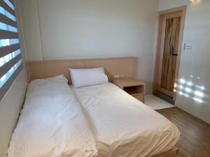 un letto bianco in una stanza con una finestra di Drizzle Tea House a Fenchihu