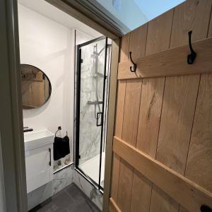 a bathroom with a glass door and a mirror at Honeysuckle Cottage & Whinfell Studio in Penrith