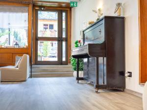 a living room with a piano and a television at Hotel Alle Alpi in Alleghe