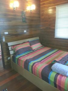 a bed in a room with wooden walls at Golden Teak Resort Baan Sapparot in Kamala Beach