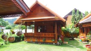 a wooden house with a porch in a yard at Golden Teak Resort Baan Sapparot in Kamala Beach