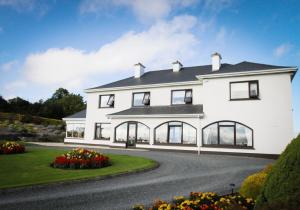 a white house with black windows and a driveway at The Arches Farmhouse B&B in Arvagh
