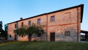 a brick building with a tree in front of it at I Salici Agriturismo in Badia Agnano