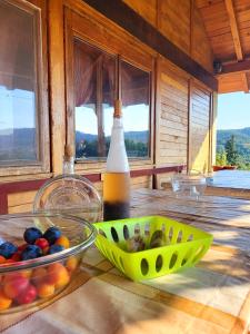 uma mesa com uma garrafa de cidra e uma taça de fruta em Venera em Kosjerić