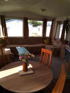 uma sala de estar com uma mesa e um sofá em Private caravan situated at Parkdean Holiday Resort St Margaret's at Cliffe number 18 em St Margarets at Cliff