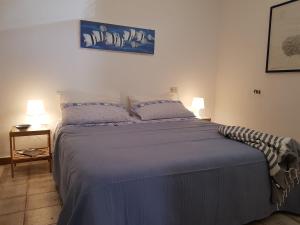 um quarto com uma cama com lençóis azuis e 2 candeeiros em Casa Ibiscus em Palazzo