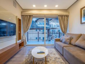 un salon avec un canapé et une grande fenêtre dans l'établissement Casa de Pedra - 301D - Apto com piscina em Gramado, à Gramado