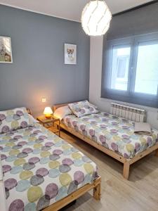 two beds in a room with two windows at Gijon playa cerca, Wifi y parking - VUT-1523AS in Gijón