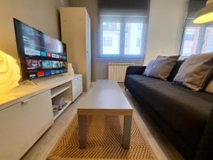 a living room with a couch and a flat screen tv at Gijon playa cerca, Wifi y parking - VUT-1523AS in Gijón