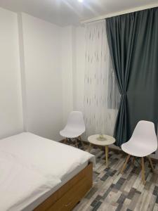 a bedroom with two white chairs and a bed at Serin Blaxy Studio in Mangalia