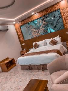 メディナにあるTaj Al Eiman Hotelの大きなベッドと大きな絵画が壁に描かれたベッドルーム1室