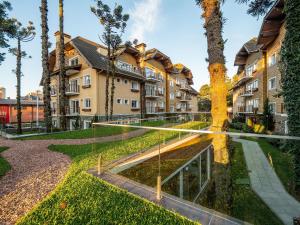 un complexe d'appartements avec une cour arborée dans l'établissement Casa de Pedra - 301D - Apto com piscina em Gramado, à Gramado