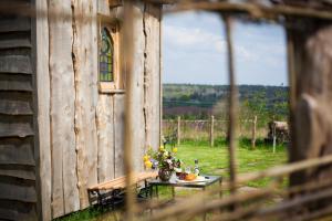 una mesa con un jarrón de flores y una ventana en The Queen Bee Cabin en Hereford