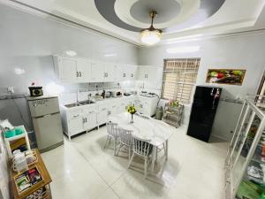 Ap My QuoにあるNina homestay P1,P4のキッチン(白いキャビネット、テーブル、椅子付)