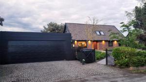 une maison avec une clôture noire et une maison dans l'établissement Falsterbo Guesthouse - Modern & Comfy, à Skanör med Falsterbo