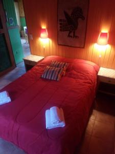 Una cama roja con dos toallas encima. en Casa al Río en El Chalten