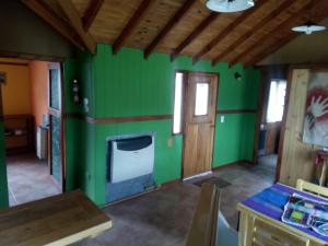 uma sala de estar com paredes verdes e um fogão em Casa al Río em El Chaltén