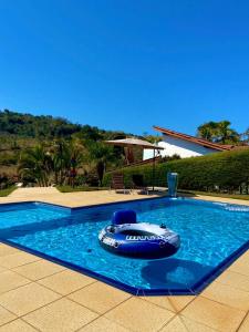 a swimming pool with a raft in the water at Chácara Santa Rita in Bom Jesus dos Perdões