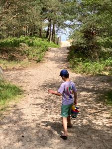 a young boy walking down a dirt road holding a toy at Lazur Park Kotwica in Gdańsk