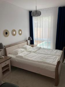 a bedroom with a white bed and a window at Lazur Park Kotwica in Gdańsk