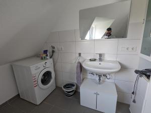 un homme prenant une photo d'une salle de bains avec un lave-linge et un lavabo dans l'établissement Schönes 2 Zimmer Appartment in der Altstadt von Koblenz, à Coblence