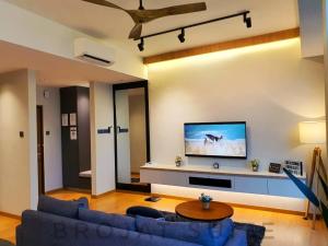 a living room with a blue couch and a flat screen tv at Brojat Suite Family City View @ Imperium Residence in Kuantan