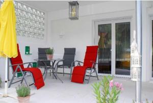 een patio met rode stoelen, een tafel en een gele parasol bij Ferienwohnung Paffendorf in Gutach