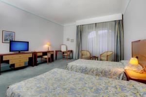 a hotel room with two beds and a flat screen tv at Hôtel Aletti Palace in Vichy